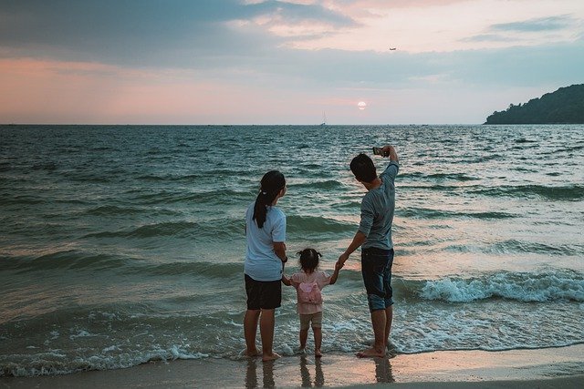 A family of three taking a selfie at the beach